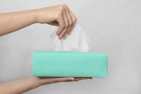 Woman taking paper tissue from box on light background, closeupの写真素材