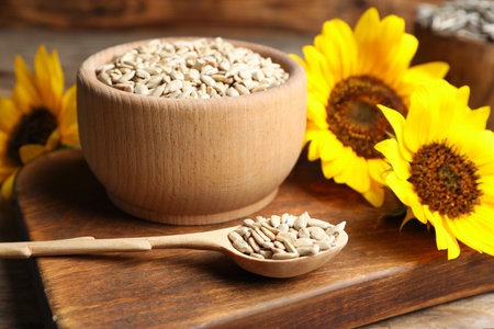 Raw peeled sunflower seeds and flowers on wooden boardの写真素材