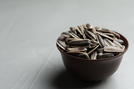 Raw sunflower seeds in bowl on gray table, closeup. Space for textの写真素材