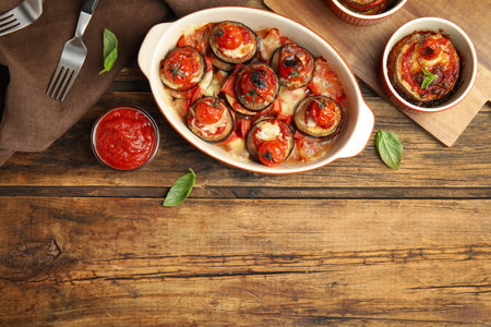Baked eggplant with tomatoes, cheese and basil served on wooden table, flat lay. Space for textの写真素材