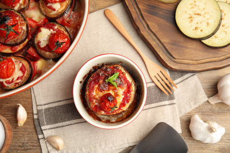Baked eggplant with tomatoes, cheese and basil served on wooden table, flat layの写真素材