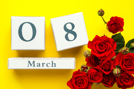 Wooden block calendar with date 8th of March and roses on yellow background, flat lay. International Women's Dayの写真素材