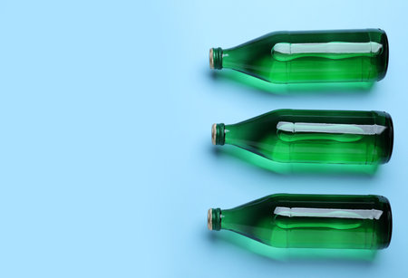 Glass bottles with water on light blue background, flat lay. Space for textの写真素材