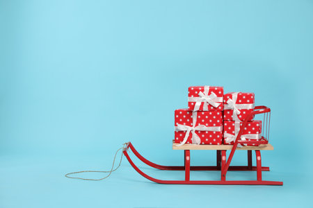 Stylish sleigh with Christmas gifts on light blue background, space for textの写真素材