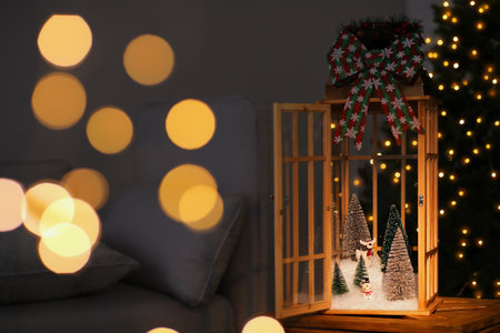 Vintage wooden lantern with beautiful Christmas composition surrounded by blurred festive lights indoorsの写真素材