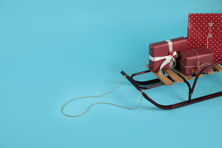 Stylish sleigh with Christmas gifts on light blue background, space for textの写真素材