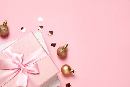 Beautiful gift boxes, golden Christmas balls and confetti on pink background, flat lay. Space for textの写真素材