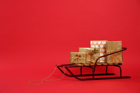 Sleigh with gift boxes on red background. Space for textの写真素材