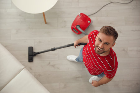 Young man using vacuum cleaner at home, top viewの写真素材
