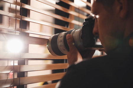 Private detective with camera spying near window indoorsの写真素材