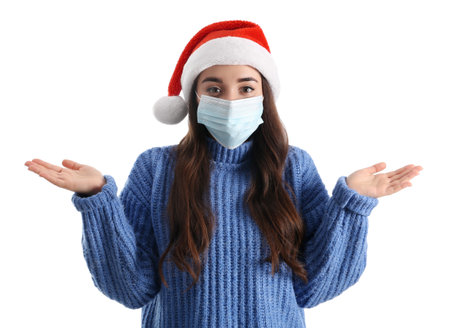 Beautiful woman wearing Santa Claus hat and medical mask on white backgroundの写真素材