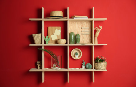 Stylish wooden shelves with decorative elements on red wallの写真素材