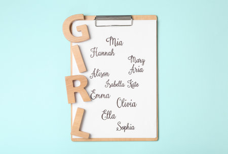 Clipboard with list of baby names and wooden letters on light blue background, top viewの写真素材