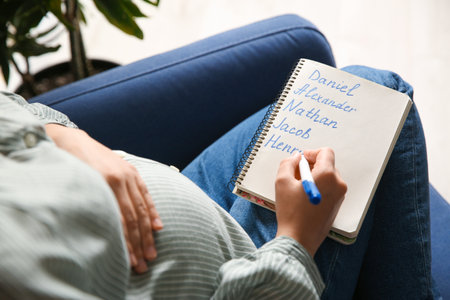 Pregnant woman with baby names list sitting in armchair, closeupの写真素材
