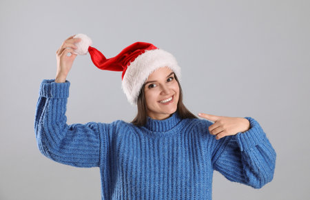 Pretty woman in Santa hat and blue sweater on gray backgroundの写真素材
