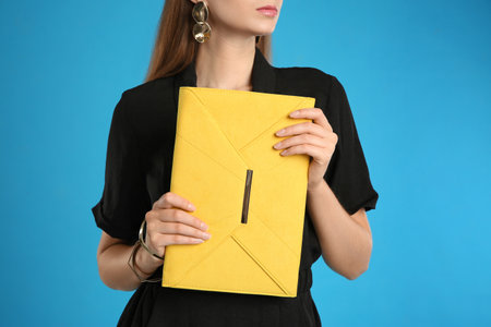 Young woman with stylish yellow bag on light blue background, closeupの写真素材