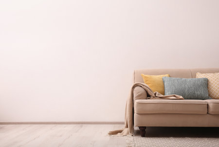 Comfortable beige sofa near light wall indoors, space for text. simple interiorの写真素材