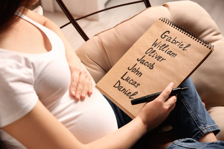 Pregnant woman with baby names list sitting in armchair, closeupの写真素材