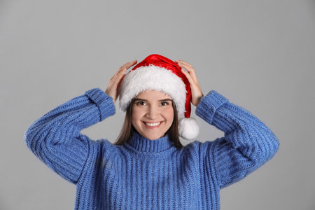 Pretty woman in Santa hat and blue sweater on gray backgroundの写真素材