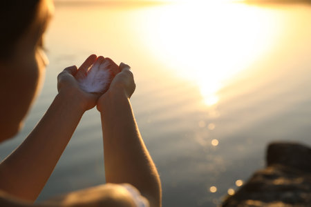 Woman with feather outdoors on sunset, closeup. Healing conceptの写真素材