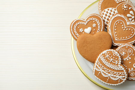 Tasty heart shaped gingerbread cookies on white wooden table, top view. Space for text