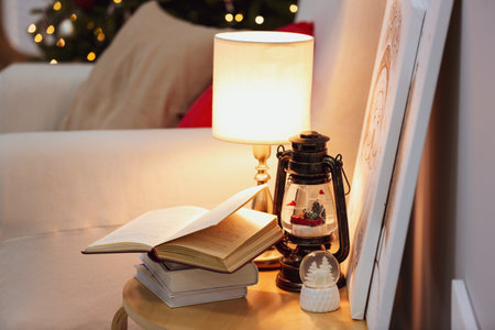 Books, snowglobes and lamp on wooden table in room. christmas decorの写真素材