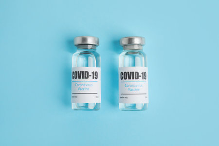 Vials with coronavirus vaccine on light blue background, flat layの写真素材