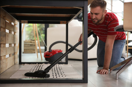 Young man using vacuum cleaner at homeの写真素材
