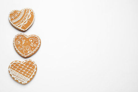Gingerbread hearts decorated with icing on white background, flat lay. Space for textの写真素材