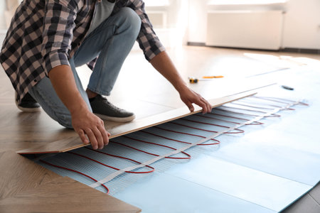 Professional contractor installing underfloor trace heating system indoors, closeupの写真素材