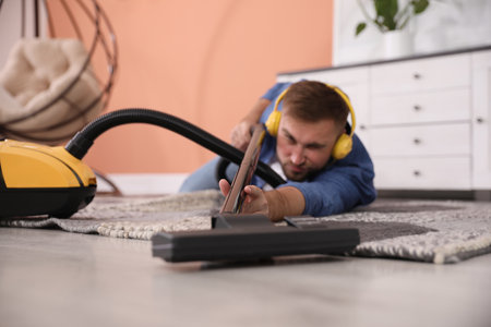 Young man having fun while vacuuming at home, focus on handの写真素材