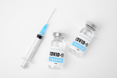 Vials with coronavirus vaccine and syringe on white background, flat layの写真素材