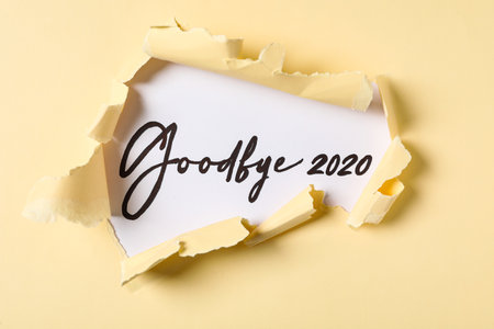 Phrase Goodbye 2020 on white background, view through torn yellow paperの写真素材
