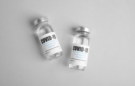 Vials with coronavirus vaccine on light background, flat layの写真素材