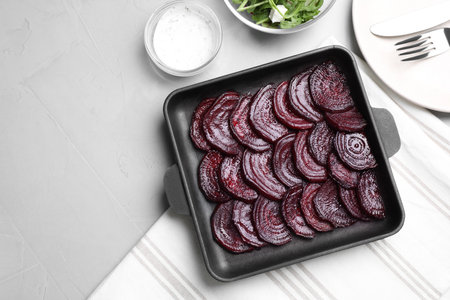 Baking dish with roasted beetroot slices on light gray table, flat layの写真素材