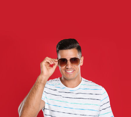 Handsome man wearing sunglasses on red backgroundの写真素材