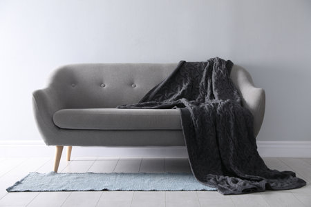 Soft knitted blanket on sofa in room. home interior
