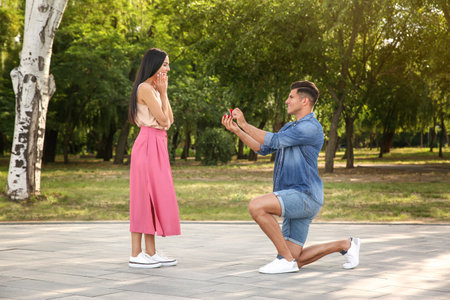 Man with engagement ring making proposal to his girlfriend in parkの写真素材