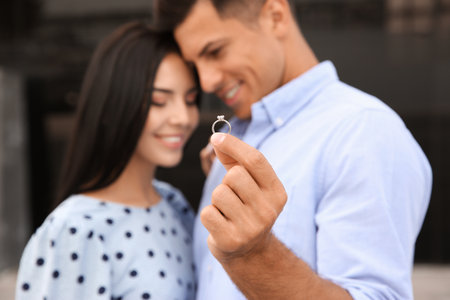 Lovely couple showing beautiful engagement ring outdoors, focus on handの写真素材