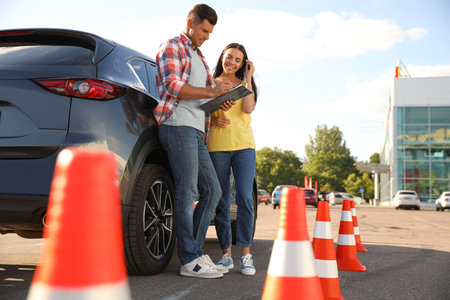 Instructor with clipboard and his student near car outdoors. driving school examの写真素材