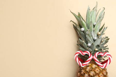 Top view of pineapple with funny glasses and festive decor on beige background, space for text. creative conceptの写真素材
