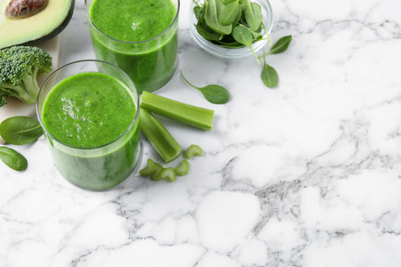 Delicious green juice and fresh ingredients on white marble table, above view. Space for textの写真素材