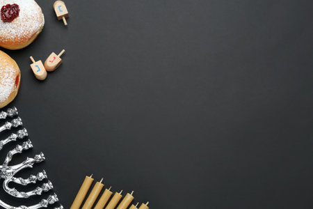 Hanukkah traditional menorah, candles, donuts, dreidels with letters He, Pe, Nun, Gimel on black background, flat lay. Space for textの写真素材