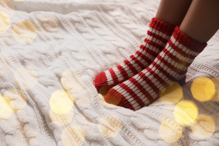 Woman in warm socks on knitted blanket, closeup. Space for textの写真素材