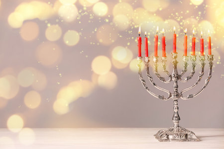 Silver menorah with burning candles on table against light background, space for text. Hanukkah celebrationの写真素材