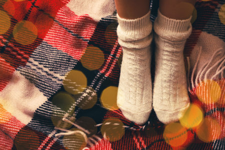 Woman in knitted socks on warm plaid, top view. Space for textの写真素材