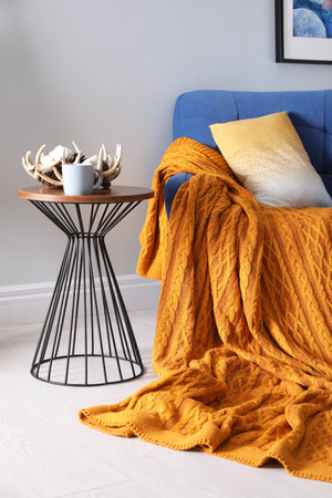 Soft knitted blanket on armchair in room. home interior