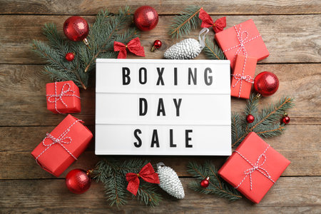 Flat lay composition with Boxing Day Sale sign and Christmas gifts on wooden tableの写真素材