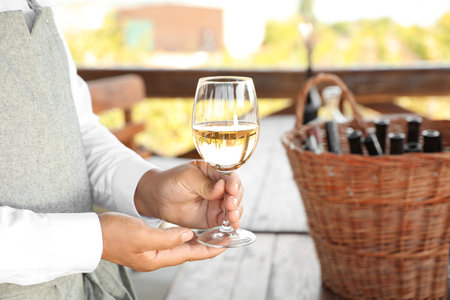 Waiter holding glass of white wine in outdoor cafe, closeupの写真素材