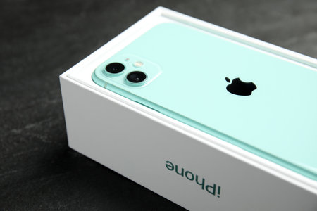MYKOLAIV, UKRAINE - JULY 10, 2020: New modern Iphone 11 Green in original box on gray table, closeup